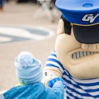 Louie fistbumps a little Laker while an alum watching smiling